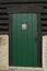 Green door and rough black painted logs on an old log cabin building