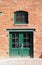 Green door and window in brick wall