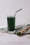 Green drink made from single-celled green algae chlorella and green chlorella powder in wooden spoon. Superfood detox in a glass