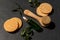 Green drop bottle with essentil oil or face serum next to matural massaging brush and cellulose sponges on black background. Face