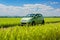 Green electric car parked in field with eco-fuel concept, cloudy landscape background