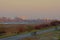 Green embankment along river Scheldt with biking path and benches, and the city on the other side