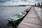 Green empty boats on the lake along the wooden pier, cloudy autumn sky against the background