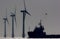 Green energy. Offshore wind farm turbines with ship at sea. Silhouette at dawn.