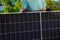 Green energy. Solar panel in the hands of a worker in a summer garden. Fitting and installation of solar panels