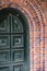 Green entrance arched door framed by brick arch of the building