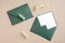Green envelopes and dried flowers on pastel beige background. Wedding invitation mockup, elegant rustic greeting card