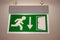 Green evacuation direction sign on ceiling. Emergency exit sign with running man on it