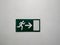 Green exit sign plate with a man figure and arrow to the door as an instruction for directions in case of an emergency