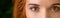 Green eyes of young redhead woman panorama