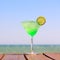 Green fairy cocktail on the wooden pier. Concept of exotic cocktail. Seaside vacation