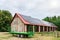 Green farm trailer parked in front of a large barn. Solar panels installed on the roof of the barn