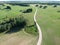 Green farmland crop fields and white gravel road, aerial