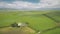 Green farmland at fields, pastures aerial. Cottages, barns at grasses meadow with farm animals