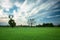 Green farmland, trees on the horizon and cool clouds on the sky