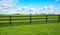 A green fence field and a blue sky. Pastures out of town.