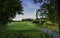 Green field with hills, trees, tee box and sand bunker on rural golf course