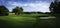 Green field with hills, trees, tee box and sand bunker on rural golf course