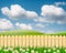 A Green field landscape from backyard with daisy flowers and wooden picket fence