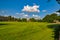 Green field with old buildings, blue sky and cloud