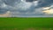 Green field and storm clouds, panoramic time-lapse