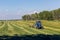 Green field in the summer of truck driving next to the combine