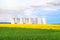 Green field, yellow rapeseed field, cooling towers of nuclear power plant in background