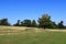 The green fields and trees under a beautiful blue sky