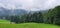 Green fields and woods with mysterious low hanging clouds over the mountains in the background. AllgÃ¤u Bavaria Germany