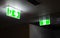 Green fire escape sign hang on the ceiling in the office at night