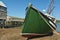 Green Fishing boat laying on side low tide