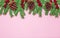 Green foam Christmas tree branch border with cones and red berries on the pink background flat lay, top view. Handmade New Year