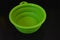 Green folding and multifunctional rubber plate, a bowl with a plastic edging on a black glossy surface.