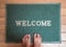 Green foot scraper mat on wooden floor with barefoot standing