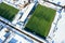 Green football field and people playing football in winter stadium. aerial view