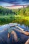 Green forest, dramatic sky, meadow and reflection in water of Cr