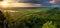 Green forest mountain at sunset with storm