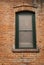 Green framed window under a brick arch