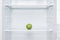 Green fresh apple lies on a shelf in an open white refrigerator