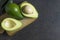Green fresh ripe avocado whole and half fruits on black rustic background