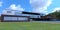 A green freshly cut meadow in front of a modern country house built according to an individual design. Blue sky with cumulus