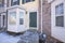 Green front door of a townhouse with vinyl wood and bricks siding