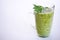 Green fruit and vegetable smoothie with a sprig of parsley in a transparent glass mug on a white background. healthy diet. food