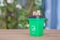 A green garbage can with food waste and a pile of dollar coins on its lid