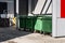 Green garbage containers on backyard of store.