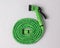 Green garden hose coiled with spray nozzle isolated