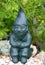 Green garden ornament gnome sitting down on stones