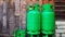 Green gas tanks on wooden wall or wallpaper with copy space on left. Group of object to make fire for cooking food in kitchen.