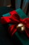 Green gift box with a red silk bow, with a gold bell on a dark background