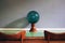 Green glass bowl with a wood base on top of a green glass table and two chairs